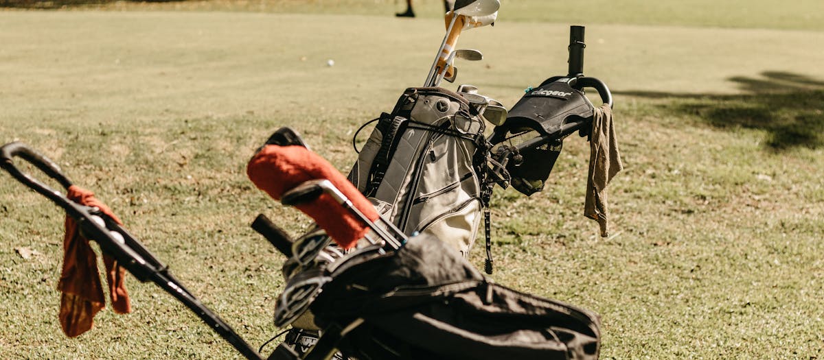 A golf bag and clubs on a sunny golf course, perfect for summer leisure.
